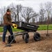 A man pushing a Gorilla poly yard dump cart with a yellow handle.