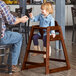 A child sitting in a Lancaster Table & Seating wooden high chair.