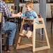 A man sitting at a table with a child in a Lancaster Table & Seating wooden high chair.