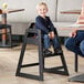 A child sitting in a Lancaster Table & Seating high chair with a black finish.