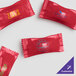 A group of red packages of customizable chocolate pastel mints with assorted candy shell and yellow, green, and blue text.