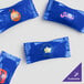 A white plastic bag filled with blue wrapped chocolate buttermints with custom printed logos.