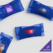 A white plastic bag filled with several blue packages of customizable chocolate pastel mints with navy wrappers.