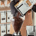 A person pouring Arrosto coffee beans into a coffee grinder.