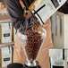 A man pouring Arrosto Nicaragua Jinotega coffee beans into a glass container.