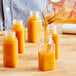 A person pouring orange juice into small square PET bottles.