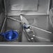 An interior view of a commercial undercounter dishwasher showing the spray arm, filter, and stainless steel tub.