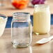 A clear glass jar with a white and yellow liquid in it and a spoon.