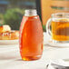 A Classic Queenline PET inverted honey bottle on a table with honey inside.