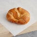 A Bridor sliced butter croissant on white paper in a bakery display.