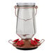 A glass jar with a metal base and red flowers on the top.