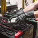 A pair of black industrial-grade rubber gloves being worn by a person working with electrical equipment.
