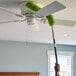 A person using a Libman Flexible Microfiber Wand Duster to clean a ceiling fan.