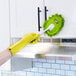 A green Libman 7 1/2" x 5" microfiber duster being used to clean a white kitchen cabinet.