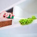 A green and white microfiber duster being used to clean a shelf.