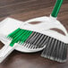 A white Libman dustpan with green accents on a wood floor.