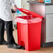 A red rectangular step-on trash can with a foot pedal and a liner inside.