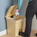 A man using a Lavex rectangular step-on trash can to throw paper in.