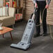 A person using an Advance Spectrum dual motor upright vacuum cleaner.