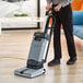 A person using an Advance SC100 upright floor scrubber to clean a hardwood floor.