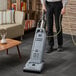 A man using an Advance Spectrum upright vacuum cleaner on a carpet.