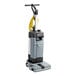 An Advance upright walk behind floor scrubber with a yellow handle.