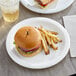 A Choice heavy weight white paper plate with a hamburger and fries on a table.