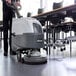 A person using an Advance SC370 walk-behind floor scrubber to clean a floor.