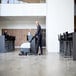 A man using an Advance SC370 walk-behind floor scrubber to clean a floor.