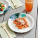 Two Choice heavy weight paper plates with pasta and a drink on a table.