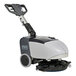 An Advance cordless walk behind floor scrubber with a handle and wheels.