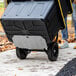 A person using a Gorilla steel hand truck to push a black and yellow container.