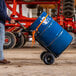 A man using a Gorilla convertible hand truck to move a blue barrel.