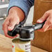 A person using the OXO Good Grips handheld can opener to open a can.