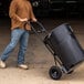 A man pushing a black container with a Gorilla steel hand truck with pneumatic wheels.