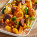 A plate of food with potatoes, broccoli, and other vegetables next to a container of Regal Chili Powder on a table.