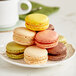 A plate of colorful macaroons with a yellow macaroon in the center.