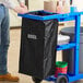 A man pushing a Lavex janitor cart with a black bag.