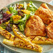 A plate of food with Tajin seasoning on corn and grilled chicken.