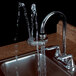 A Haws Axion EyePOD 7620 faucet-mount eye wash station with water flowing from it.