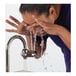 A woman washing her face with water running from a Haws faucet.