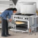 A woman putting food in a Wolf commercial gas oven.