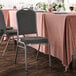 A Lancaster Table & Seating gray fabric crown back banquet chair with a silver vein frame next to a table set for a dinner.