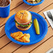 A blue plastic Choice plate of food with a hamburger and chips on a table.