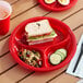 A Choice red plastic plate with a sandwich on it.