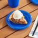 A blue plastic plate with a slice of pie and a scoop of ice cream on it.