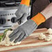 A person wearing Armor Guys Kyorene Pro cut-resistant gloves cutting cauliflower on a cutting board.