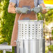 A man using a Choice aluminum steamer basket in a large stock pot.