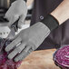 A person wearing a gray Armor Guys Kyorene Pro cut-resistant glove cutting a red cabbage on a wooden surface.