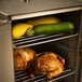 A chicken and zucchini cooking in a SmokinTex electric smoker with vegetables.